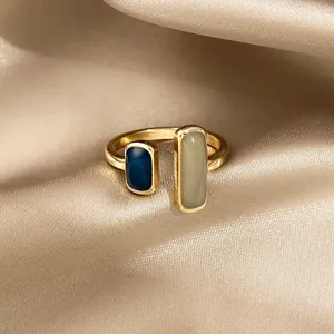 Primo piano di un anello aperto geometrico placcato oro con smalto blu e grigio