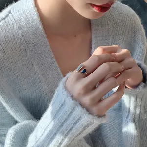 Primo piano di un anello aperto geometrico minimalista con smalto blu e grigio