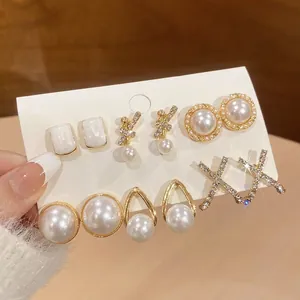Detailed view of six pairs of elegant pearl and crystal earrings on a white card