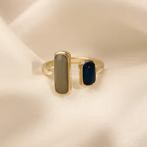 Primo piano di un anello aperto geometrico con smalto grigio e blu scuro