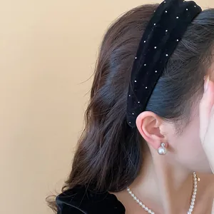 Detailansicht eines eleganten schwarzen gepunkteten Samthaarbands mit Perlenohrring