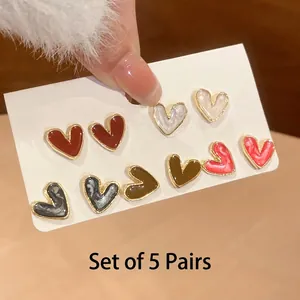 Detail view of five pairs of colorful heart-shaped oil-drop stud earrings on white card