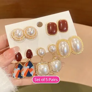 Close-up of a 5-pair set of French vintage pearl and enamel earrings on a card