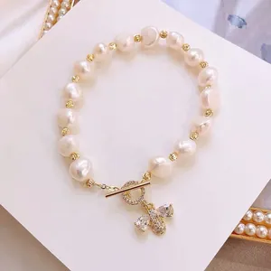 Detailed macro view showing a freshwater pearl bracelet with micro-paved honeybee charm