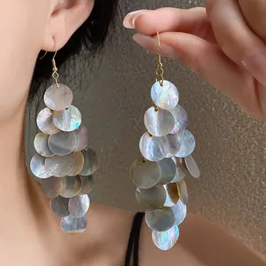 Gros plan de boucles d'oreilles en nacre irisée au style bohème très élégant.