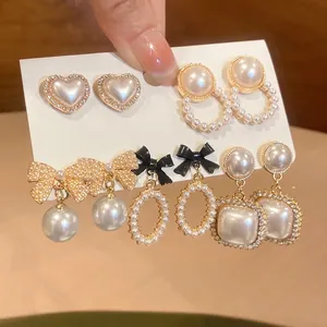Detailed close-up view of five pairs of elegant French-style pearl earrings on card