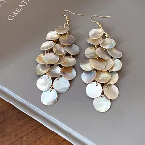Vue détaillée montrant l'éclat iridescent des disques de coquillages sur ces boucles.