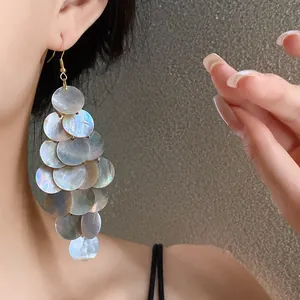 Vue détaillée de boucles d'oreilles à pampilles en nacre sur un mannequin.