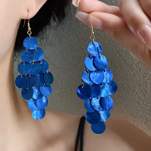 Gros plan détaillé de boucles d'oreilles pendantes en nacre bleue sur un modèle