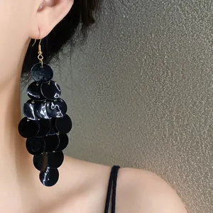 Gros plan de boucles d'oreilles noires en disques de nacre superposés