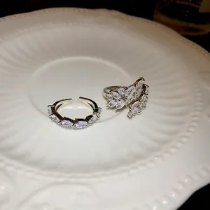 Eleganti anelli aperti geometrici in zircone color argento su un piatto bianco