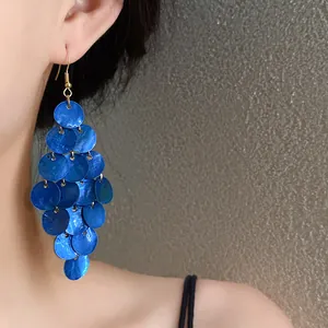 Vue détaillée de boucles d'oreilles pendantes à pampilles en nacre bleue de style.
