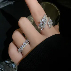 Dettaglio di un elegante anello aperto argentato con zirconi brillanti a forma di foglia.