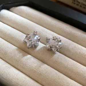 Close-up detail of elegant star-shaped stud earrings with zircon and pearlescent finish.