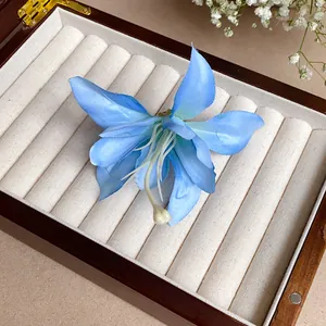 Détail d'une pince à cheveux fleur de lys bleue posée dans une boîte à bijoux en bois