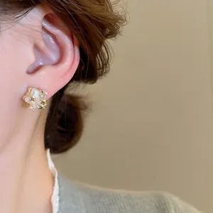 Close-up of elegant star pearl stud earrings with sparkling zircon accents on ear.