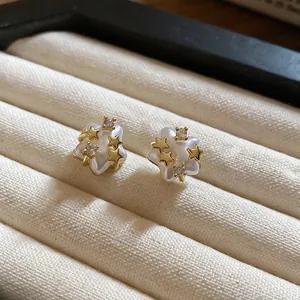 Close-up of elegant gold star stud earrings with pearl finish and sparkling zircons