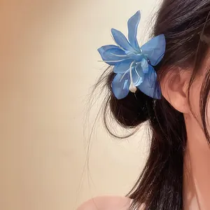 Vue détaillée d'une pince à cheveux en forme de fleur de lys bleu portée par un modèle