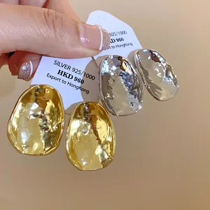Detailansicht modischer gold- und silberfarben gehämmerter ovaler Ohrstecker mit Textur