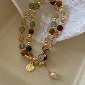 Close-up of baroque pearl and crystal double-layer bracelet with a gold coin charm