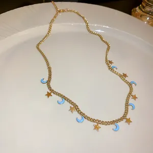Detailed macro view of a gold chain necklace with blue crescent moon and gold star charms.