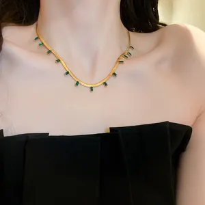 Close-up of gold snake chain necklace with emerald green zircon pendants on neck
