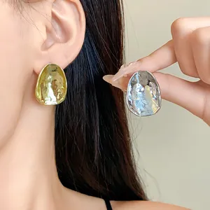 Nahaufnahme der strukturierten Gold- und Silberohrstecker am weiblichen Model.
