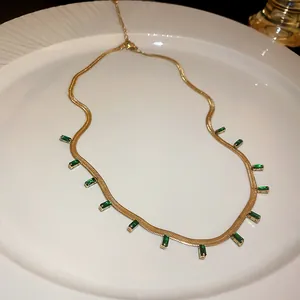 Gold-tone titanium steel necklace with rectangular emerald green zircons on white plate