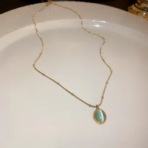 Close-up of elegant gold necklace featuring an oval light green cat's eye stone pendant