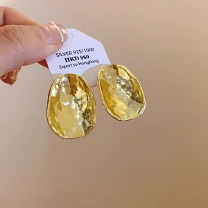 Detailansicht goldener Ohrringe mit gehämmerter Textur und Nadeln aus 925er Silber für Damen