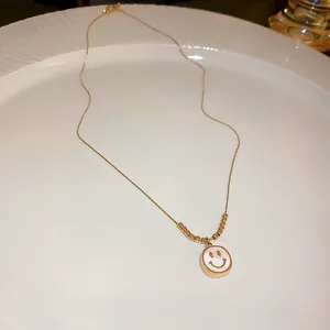 Detailed macro view of a golden smiley face pendant necklace on an elegant white ceramic plate