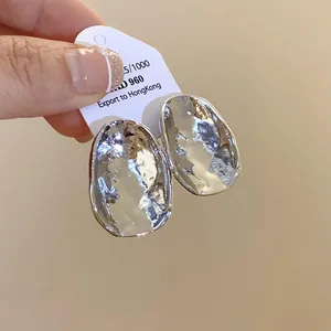 Detailansicht der silbernen unregelmäßigen ovalen Ohrstecker mit Hammerschlag-Textur