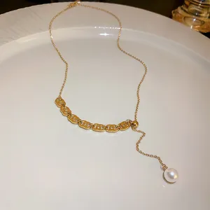 Close-up of elegant gold titanium steel necklace with pearl drop and C-pattern links