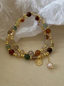 Close-up of double-layered bracelet with colorful crystals, coin charm, and baroque pearl