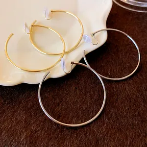Detail view of simple gold and silver hoop clip-on earrings with silicone pads.