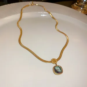 Close-up detail of a titanium steel necklace featuring a green emerald zircon pendant