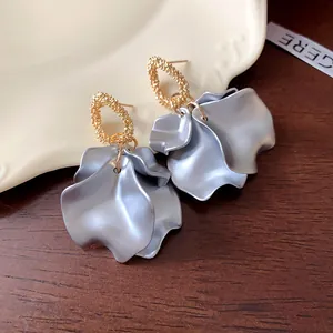 Dettaglio di orecchini vintage con petali stropicciati in eleganti tonalità oro e argento