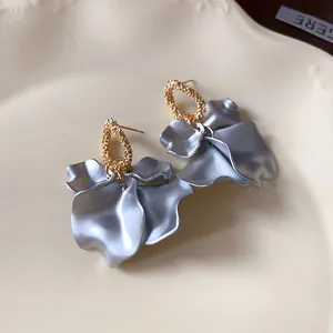 Dettaglio di eleganti orecchini a petalo pieghettato con finitura in argento e oro.