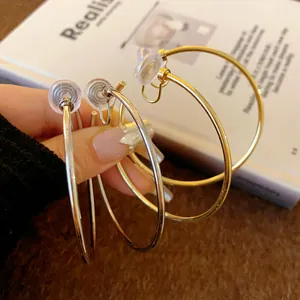 Close-up of minimalist gold and silver round hoop ear clips for non-pierced ears