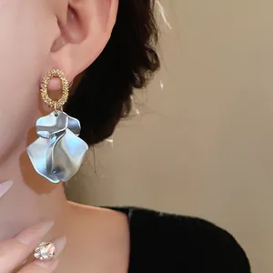 Dettaglio orecchini a petalo blu metallizzato con perni dorati testurizzati su orecchio modello
