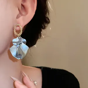 Dettaglio di eleganti orecchini a petalo blu perla con cerchio dorato martellato