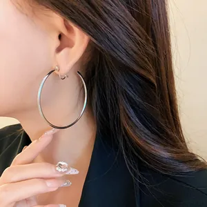 Close-up macro view of minimalist large silver hoop clip-on earrings on model's ear