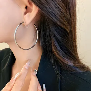 Close-up of minimalist large silver hoop earring elegantly worn by a model for detail view