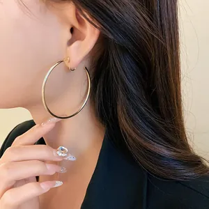 Close-up detail of a model wearing large minimalist gold hoop ear clips for non-pierced ears