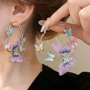 Detail shot of large silver hoop earrings featuring purple embroidered and crystal butterflies.