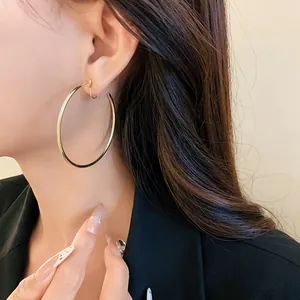 Close-up of minimalist large gold hoop clip-on earring worn by model.