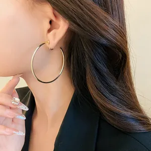 Close-up detail of minimalist large gold hoop clip-on earrings worn by a model