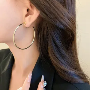 Close-up detail of a large minimalist gold hoop clip-on earring worn by an elegant model