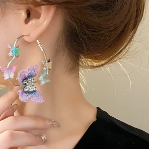 Detailed close-up showing heart-shaped hoop earring with vibrant 3D butterflies and rhinestones