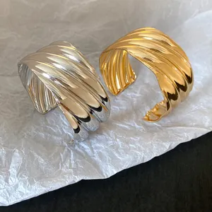 Close-up detail of stylish wavy textured metal cuff bracelets in gold and silver finishes